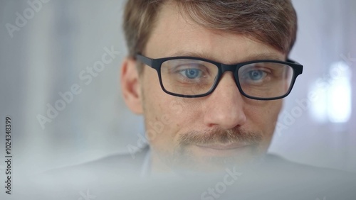 Businessman with glasses looking intently obscured partially by a translucent surface of laptop. Business concept