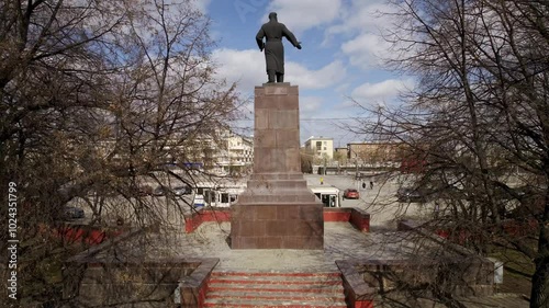 Aerial view of Monument to Ordzhonikidze in a Yekaterinburg city with oval square and low buildings. Cars drive along the ring road