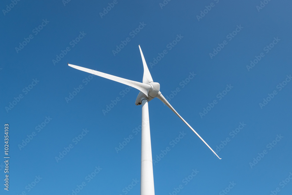 Turbina eólica com as suas grandes pás a gerar eletricidade num dia ensolarado Turbina eólica com as suas grandes pás a gerar eletricidade num dia ensolarado