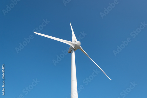 Turbina eólica com as suas grandes pás a gerar eletricidade num dia ensolarado photo