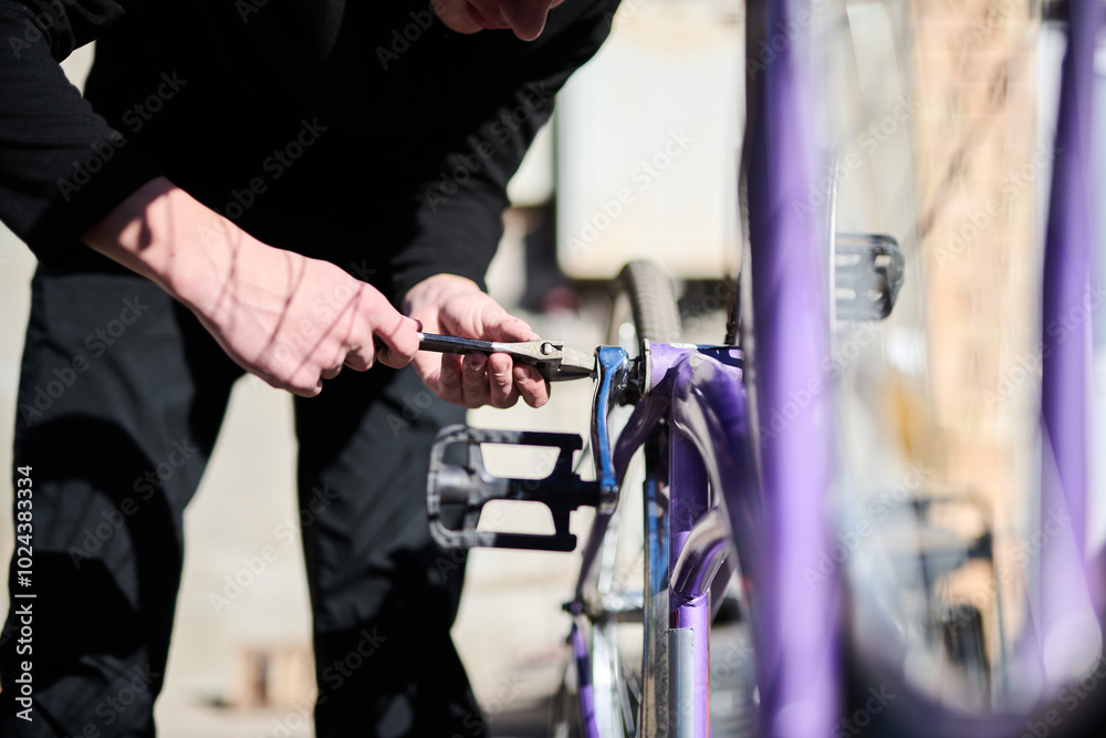 Obraz premium Young guy fixing a bicycle outside