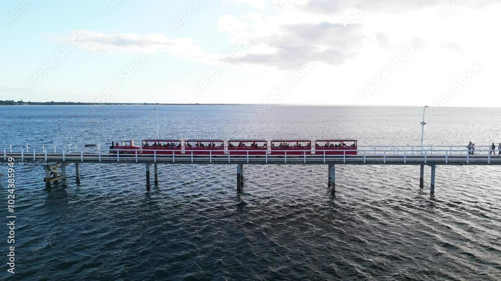 Drone flying alongside the train on Busselton Jetty at sunset Drone flying alongside the train on Busselton Jetty at sunset