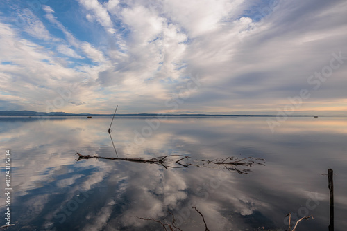ampia composizione panoramica che mostra parte dell'area del Golfo di Trieste, nel mare Adriatico, con un cielo azzurro e parzialmente nuvoloso che si riflette sullo specchio d'acqua ferma photo