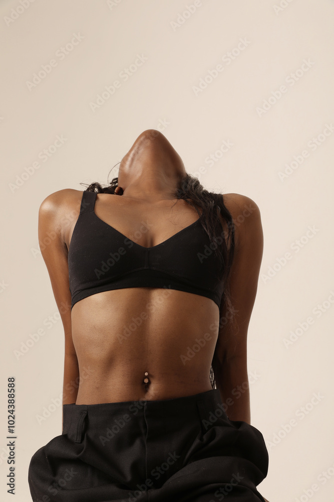 Naklejka premium Headshot of beautiful dark-skinned woman with perfect body posing indoor. 