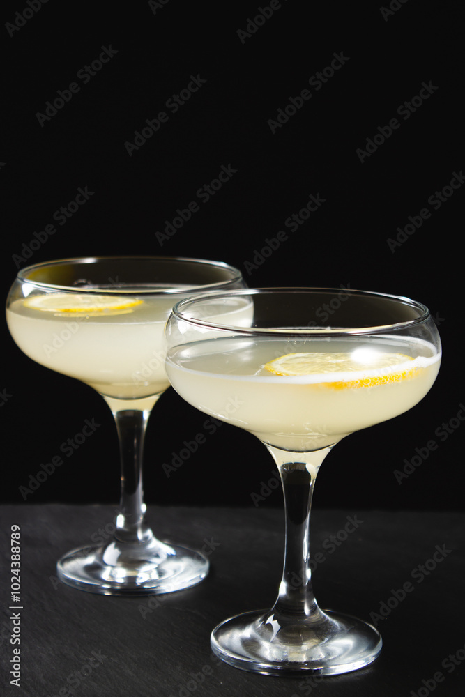 Yellow cocktail with lemon wedge on black background Yellow cocktail with lemon wedge on black background