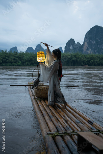 Hanfu Girl holding a lantern on a bamboo raft, Xingping, China. Vertical