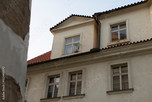 There is a charming white building that features a red tile roof, adorned with a few windows that allow natural light to enter