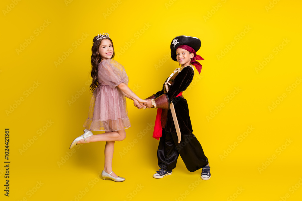 Full size photo of two little kids hold arms halloween pirate princess costume isolated on yellow color background
