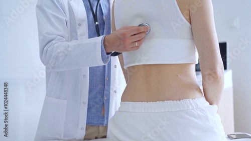 Doctor man using stethoscope examining female patient lungs duri photo