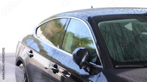 Young man cleaning car using high pressure water on self-service car wash. 