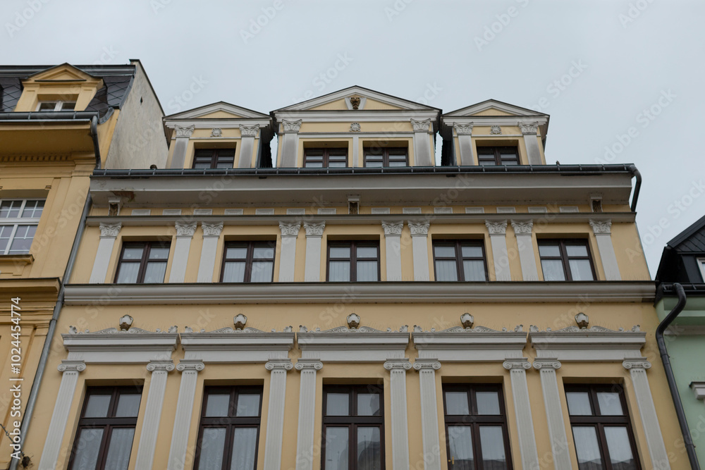 Obraz premium A very large and striking yellow building is adorned with numerous windows that create an interesting visual effect