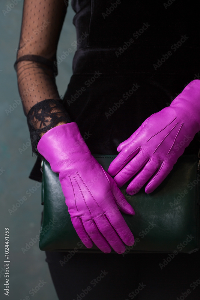 Female hands in bright fuchsia gloves hold a green handbag