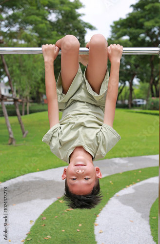 Fotografía Portrait of Asian boy child hanging upside down on equipment at playground in garden
