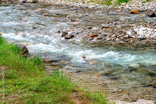 Rushing Shimagawa river stream with pebbles and grass-covered banks, Shima Onsen, Gunma, Japan. October 2024 photo