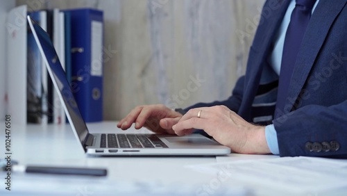 Businessman with blue suit is working on his laptop, typing on the keyboard in the office. Business concept