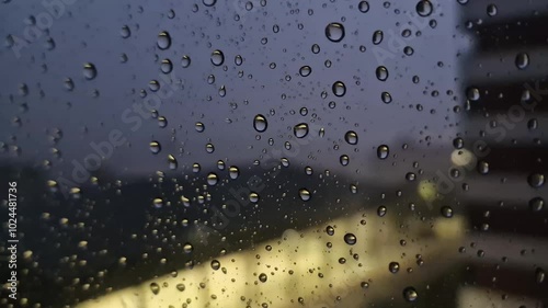 storm behind the glass, see how the raindrops crash against the glass pushed by the wind, focusing in the foreground on the impacted drops, while in the background, out of focus, the lightning,