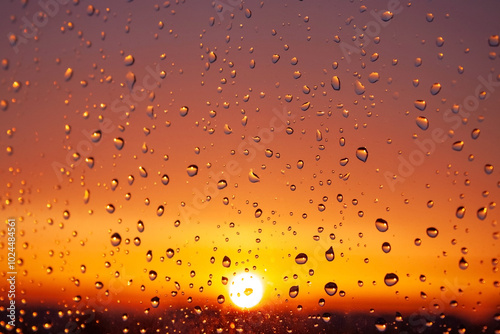 A window with raindrops on it and a sun in the background