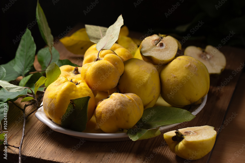 Ripe yellow quince fruits on a plate on a wooden table