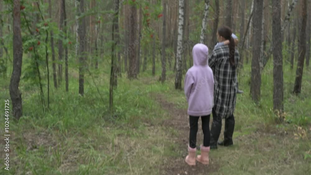 Mother with children walks through the forest, picking mushrooms, berries and herbs Mother with children walks through the forest, picking mushrooms, berries and herbs