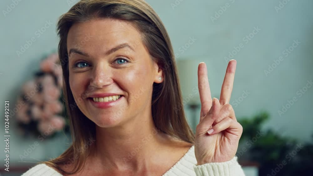 Woman with long hair making different facial expressions, including smiling and making the peace sign, in slow motion