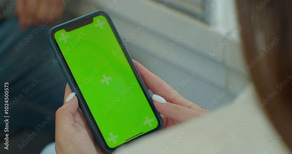 Close up of a woman hand holding a mobile telephone with a vertical blue screen in tram chroma key smartphone technology cell phone.