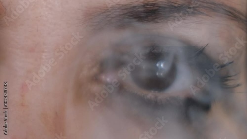 woman, whose make-up has runny from crying, smokes a cigarette and looks through the smoke.