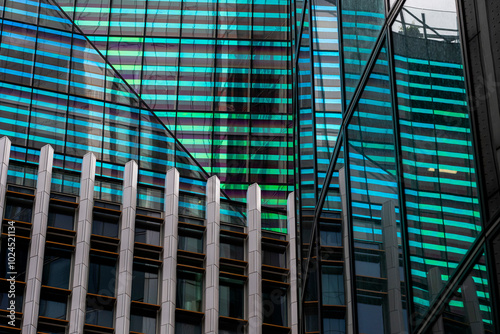 An innovative glass building facade with teal and purple striped reflections creating a vibrant, dynamic atmosphere representing modern design and color play.