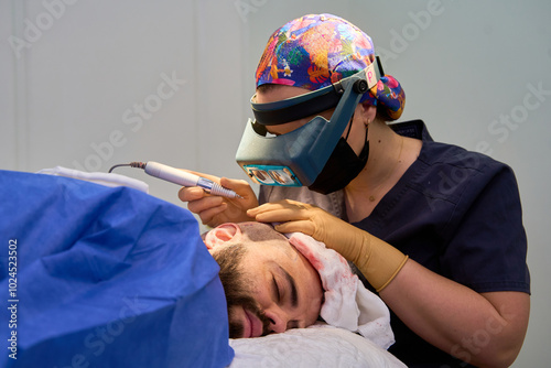 Surgeon conducting hair transplant on resting patient photo