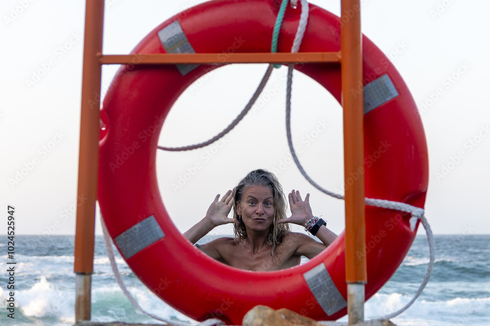 Blonde woman with bikini behind a rescue float with the sea in the background, making gestures with her face and hands. Baywatch Blonde woman with bikini behind a rescue float with the sea in the background, making gestures with her face and hands. Baywatch