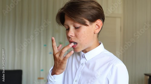a teenage boy is shown preparing to wear a silicone aligner for straightening his teeth. The video captures a close-up of him placing the aligner into his mouth, ensuring it fits snugly over his teeth