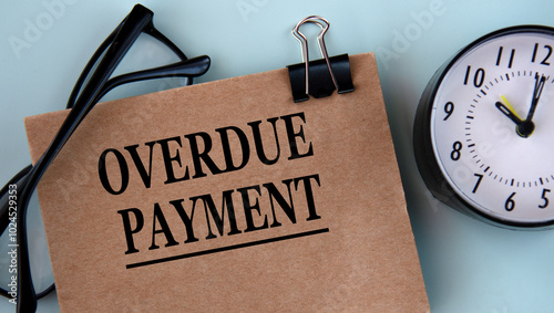 OVERDUE PAYMENT - words on brown paper on a light background with glasses and a clock