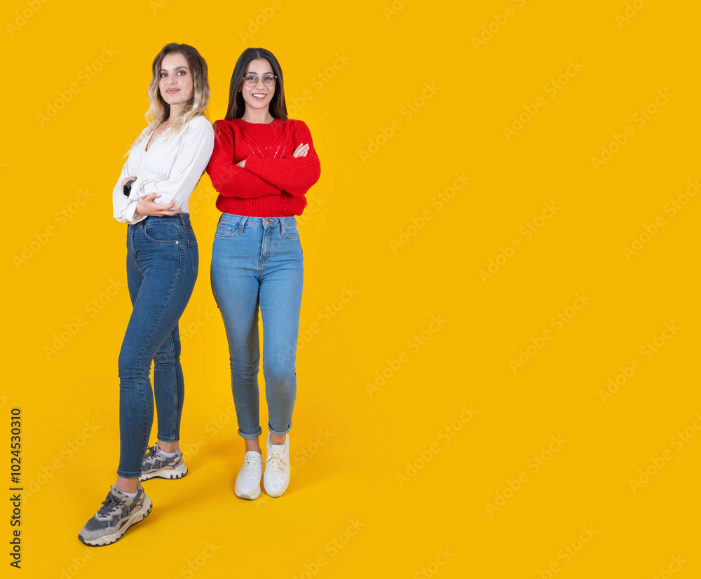 Style and confidence concept, full body view two cool caucasian women standing together over yellow background. Self confident female friends posing camera. Wear casual jean and long sleeve shirts. Style and confidence concept, full body view two cool caucasian women standing together over yellow background. Self confident female friends posing camera. Wear casual jean and long sleeve shirts.