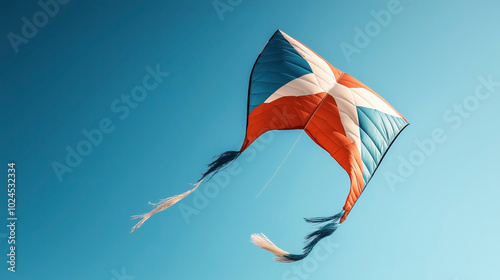 Colorful kite with red, white, and blue patterns flying against a clear sky on a sunny day. photo