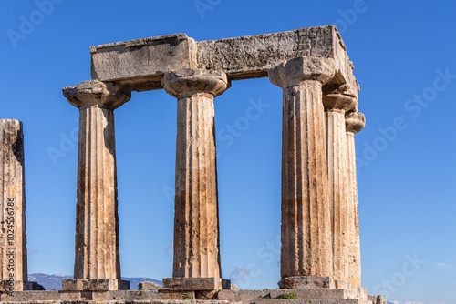 Corinth Temple of Apollo, Ancient ruins with weathered stone columns under a clear blue sky, Greek classical architecture. Corinth, Greece