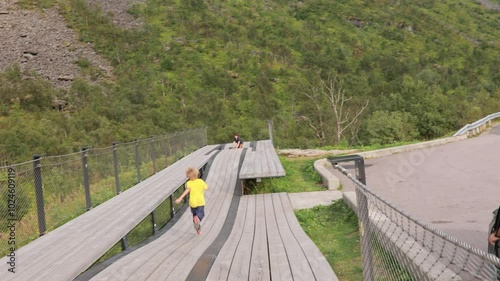 Children, standing on the edge of a 44 meter long viewing platform, overlooking the water of Bergsfjord, enjoying the view on Senja island, Norway photo