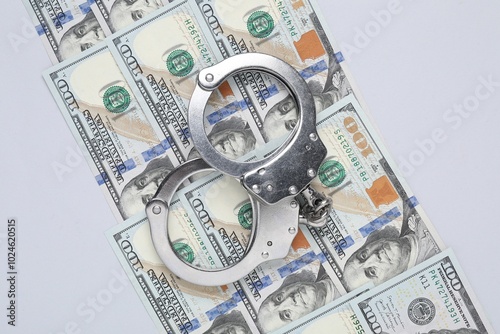 Corruption concept. Handcuffs and dollar banknotes on grey background, top view