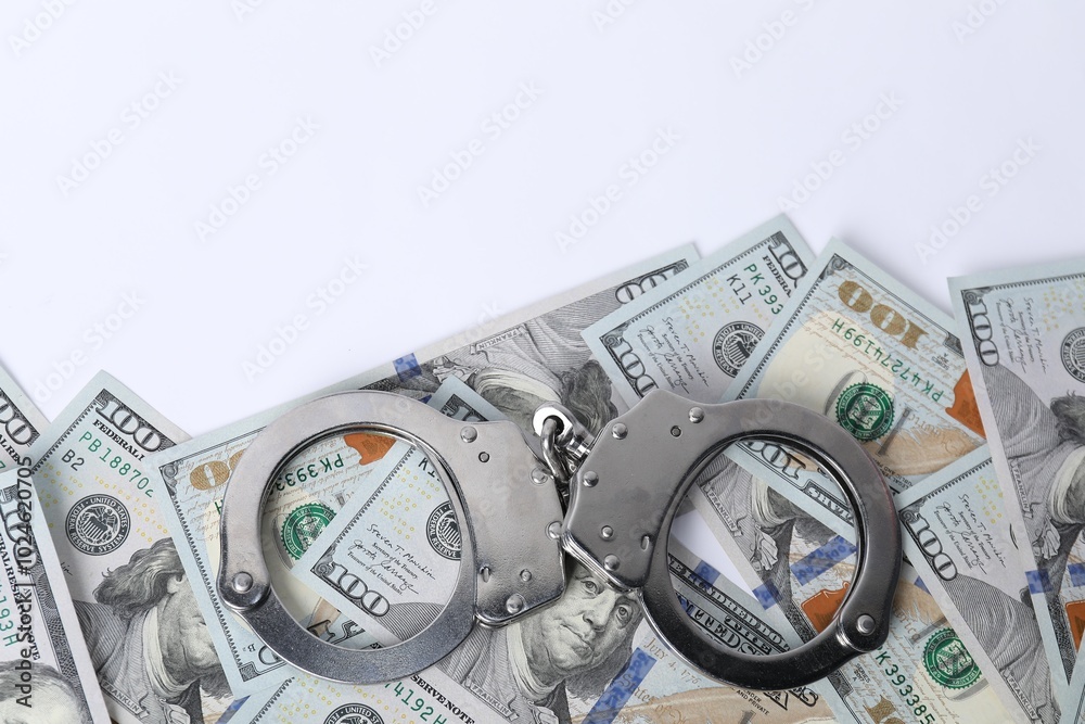 Corruption concept. Handcuffs and dollar banknotes on white background, top view Corruption concept. Handcuffs and dollar banknotes on white background, top view