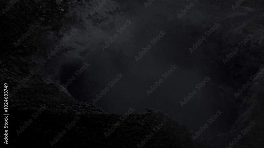 A hole in the ground from which ominous smoke or fog rises. Awesome black and white video for Halloween