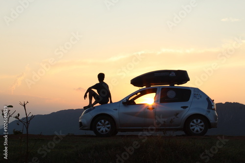 silhueta de homem sentado em carro no por do sol 