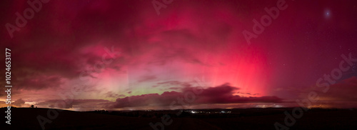 Aurora borealis in Saxony, Germany in the night of the 10. and 11. October 2024. Vibrant glowing northern lights visible at latitude 51 degrees north. Landscape at night with a cloudy sky. photo