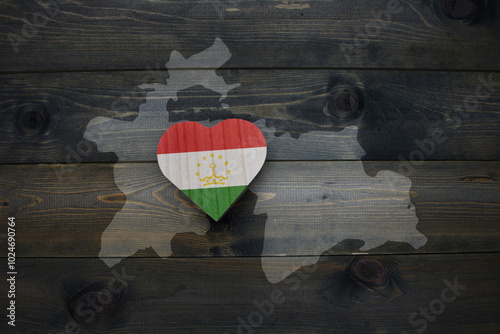 wooden heart with national flag of tajikistan near map on the wooden background. photo