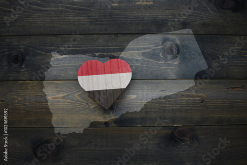 wooden heart with national flag of yemen near map on the wooden background.