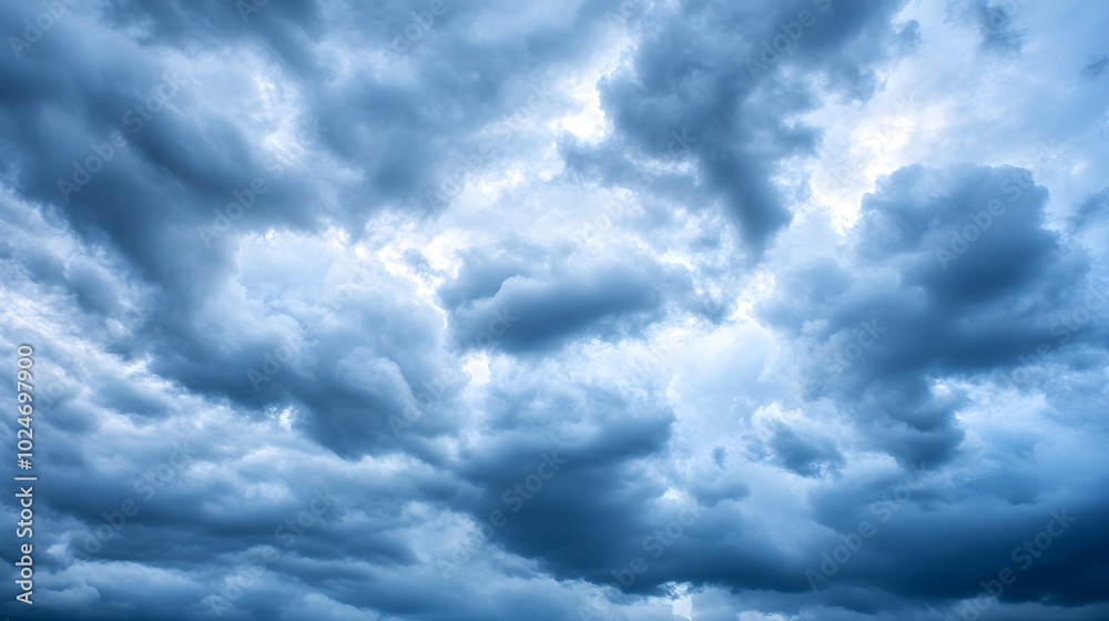 Fototapeta premium A dramatic scene of an overcast sky filled with dark, swirling clouds, suggesting an impending rainstorm, creating a moody atmosphere with varying shades of gray 