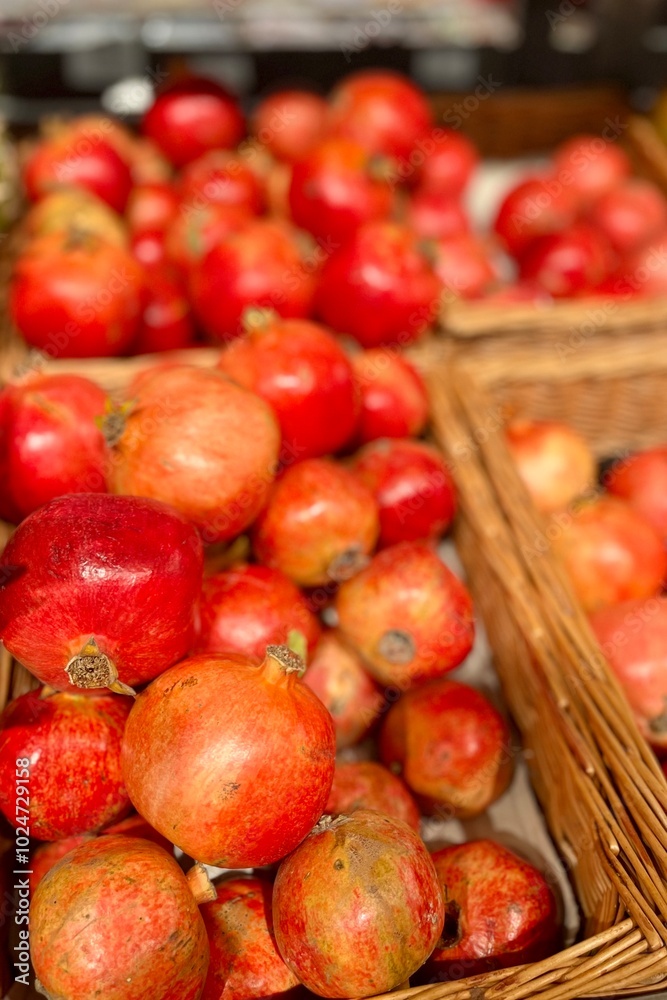 There are many red juicy pomegranates in wicker brown baskets in the supermarket. food sale. juicy fruits. copy space There are many red juicy pomegranates in wicker brown baskets in the supermarket. food sale. juicy fruits. copy space