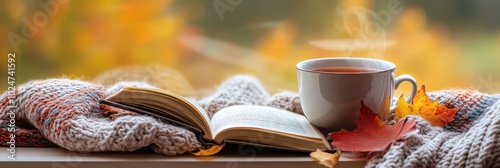 Cozy Autumn Retreat, a steaming cup of tea, a warm blanket, an engaging book, vibrant autumn leaves outside the window photo