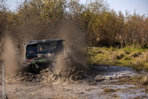 Off road buggy crossing water obstacle in a bog terrain making a lot of splashes