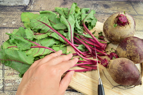 Cutting leaves from fresh beetroots on wooden board photo