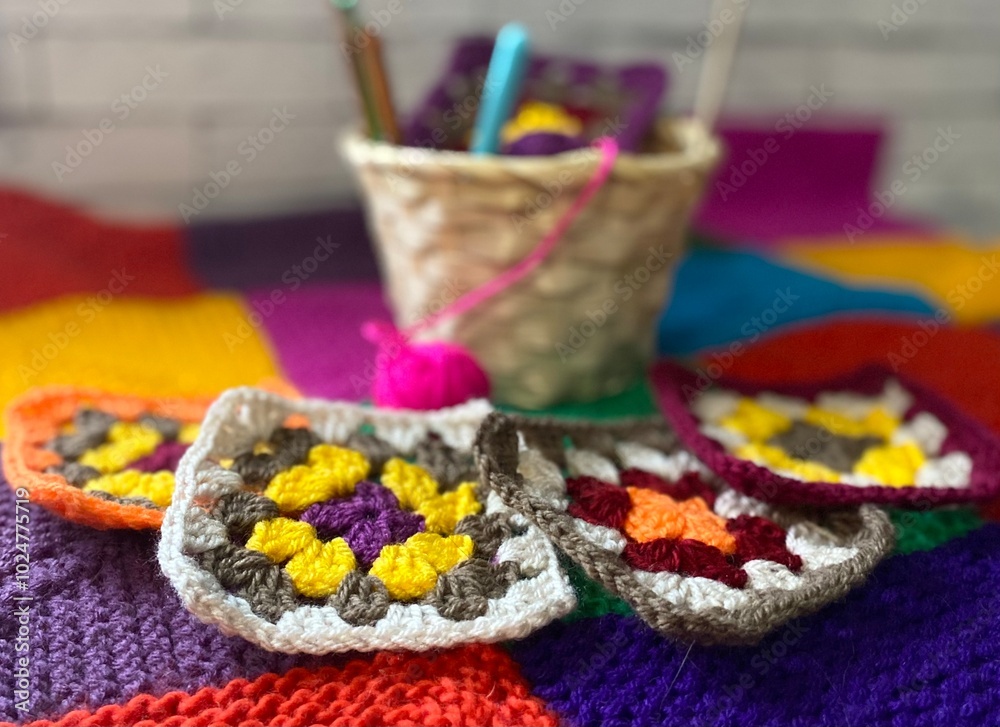 Crochet granny square, clews and hook on knitted blanket background photo Crochet granny square, clews and hook on knitted blanket background photo