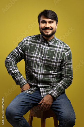 man sitting, smiling, with one hand on his waist