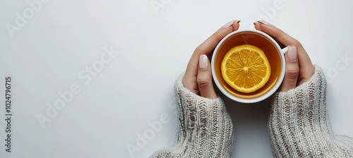 Warm cup of tea with lemon slices in cozy hands wearing knitted sweater